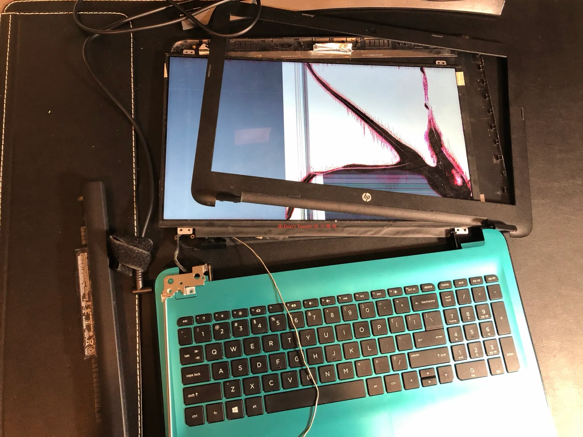 A laptop with a cracked screen and the bezel removed, before the panel swap